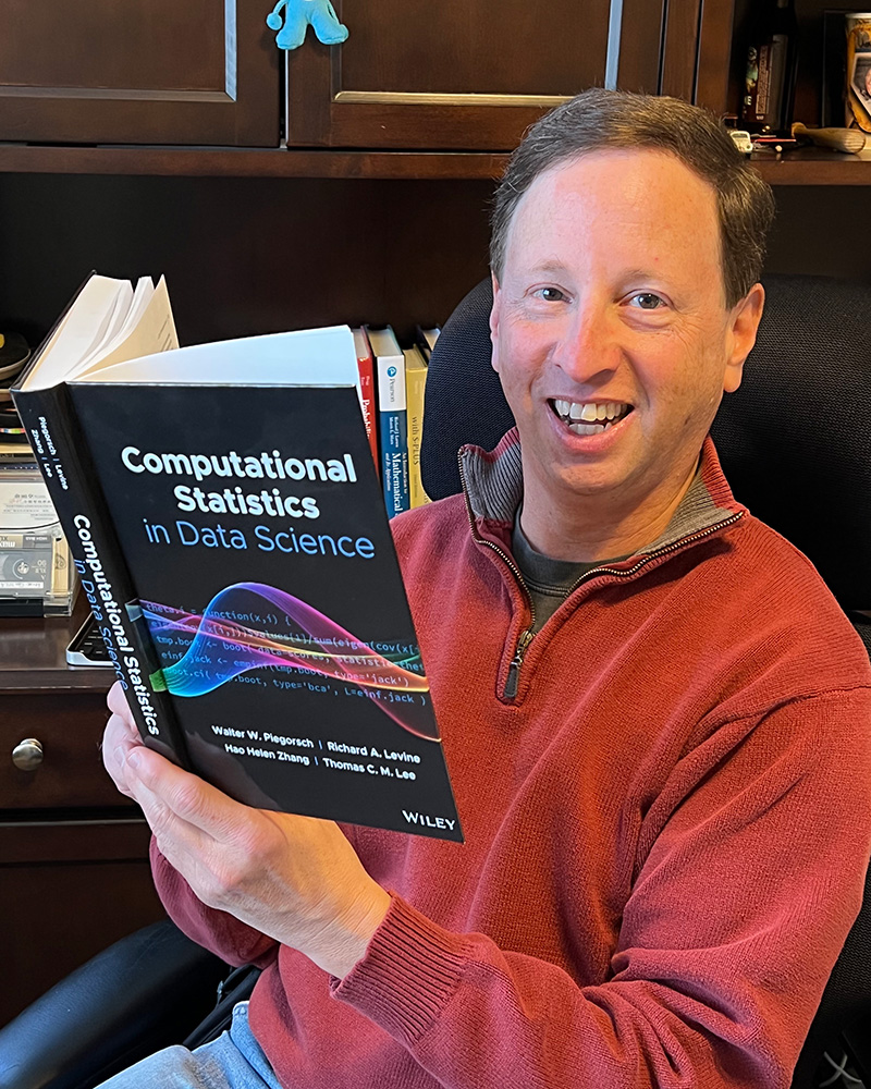 Rich Levine smiles while holding his published book
