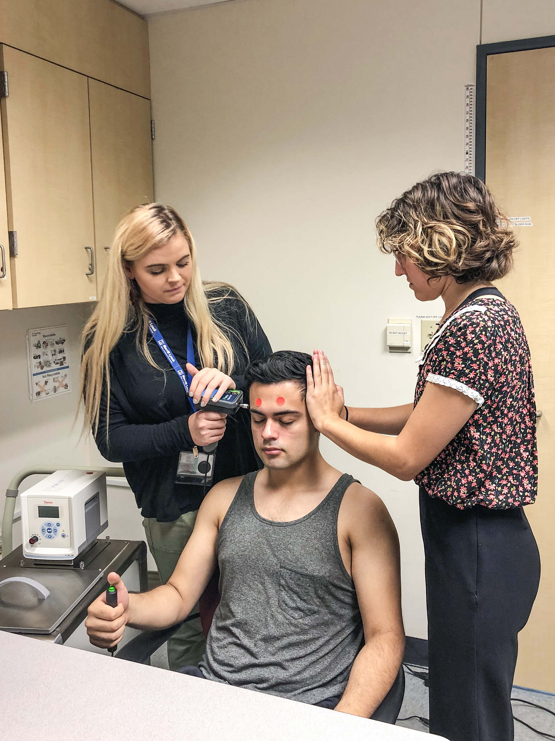 Research assistants Tiana McMann (left) and Nicole Whiteley (right) assess pressure pain thresholds in the temporalis muscle