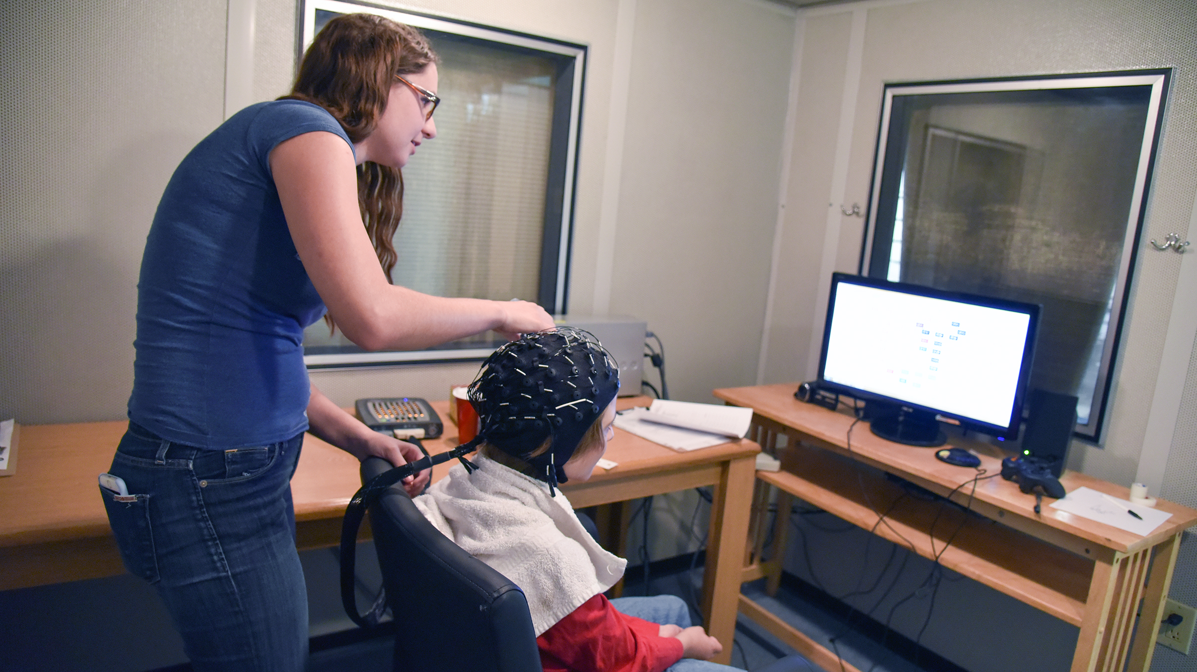 A child research participant receiving EEG testing, with research assistant Kirsten Miller.
